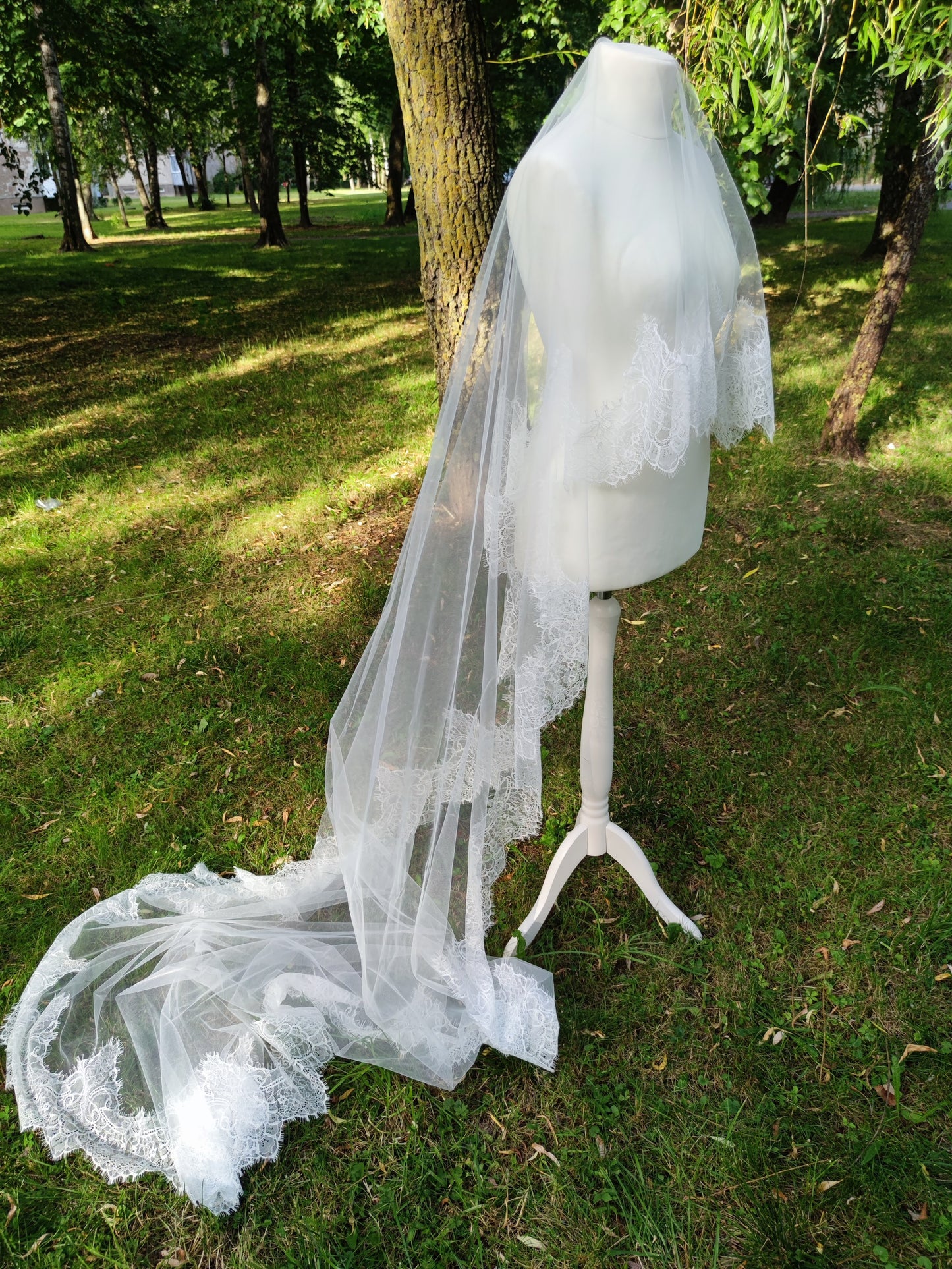 Chantilly lace mantilla cathedral veil with blusher in light ivory displayed on mannequin outdoors