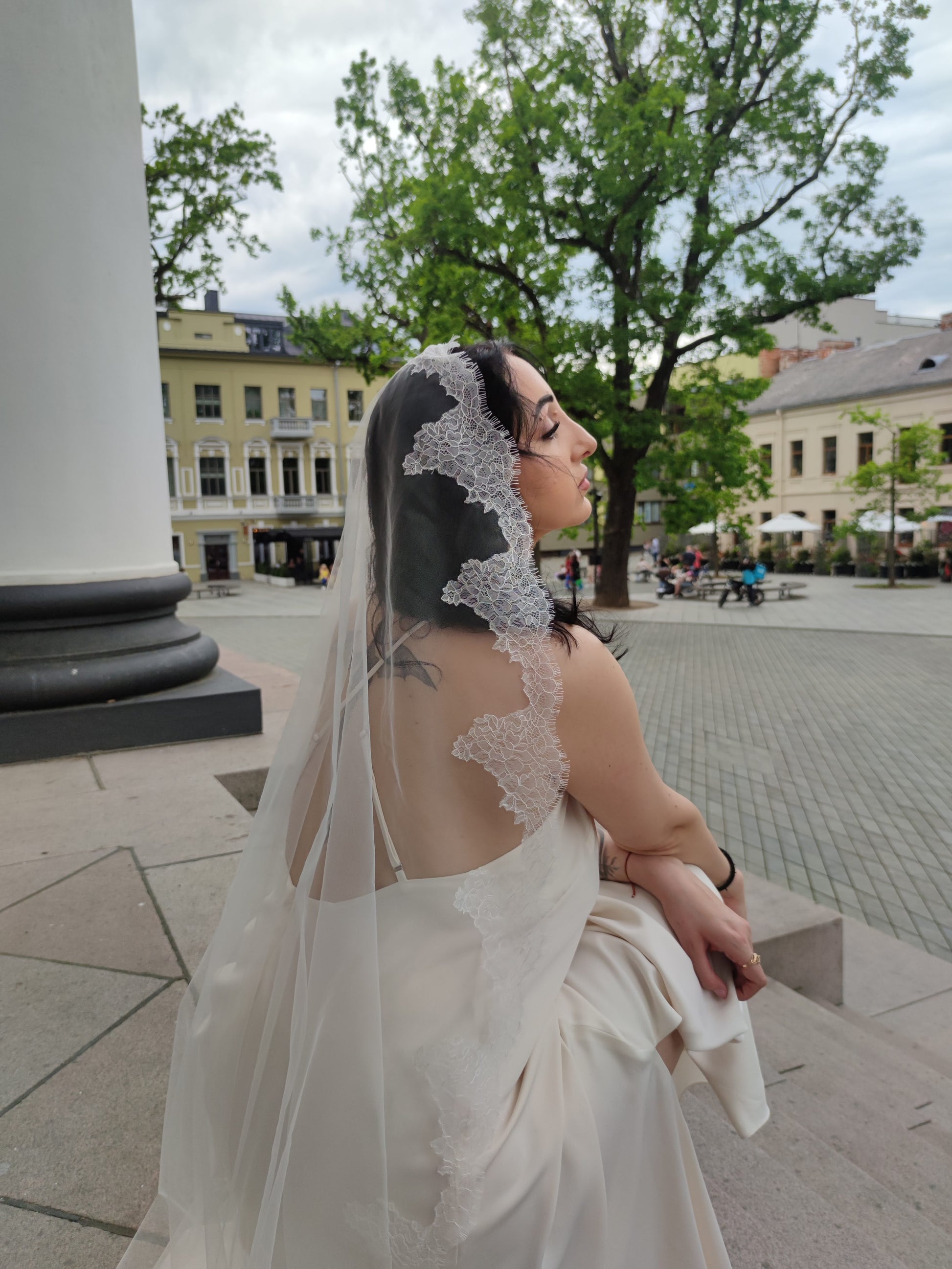 The Laima single-tier Chantilly lace mantilla veil in light ivory with scalloped floral lace edge, bride back view