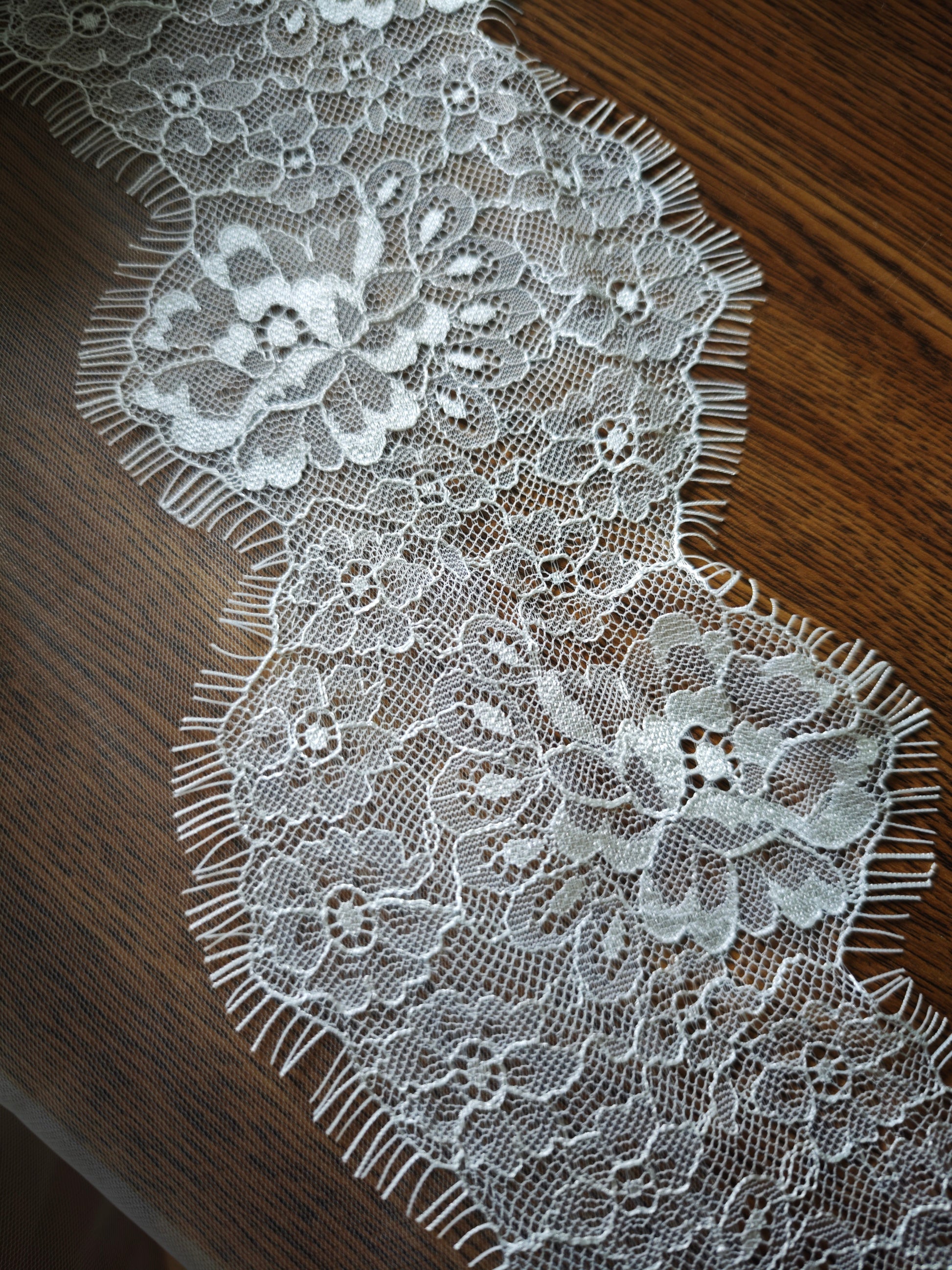 Close-up of hand-sewn floral Chantilly lace trim, showing the delicate scalloped pattern of the Medeina veil