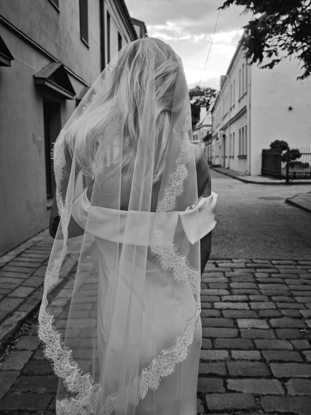 Back view of ivory mantilla wedding veil draped over hair and shoulders, delicate Chantilly lace hem