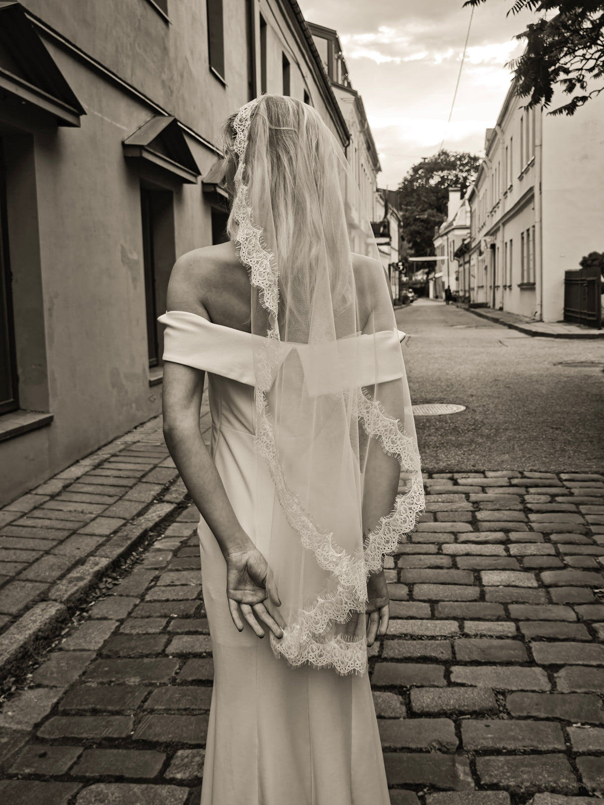 Bride from behind in a single-tier mantilla veil with hand-sewn Chantilly lace along the sides and hem