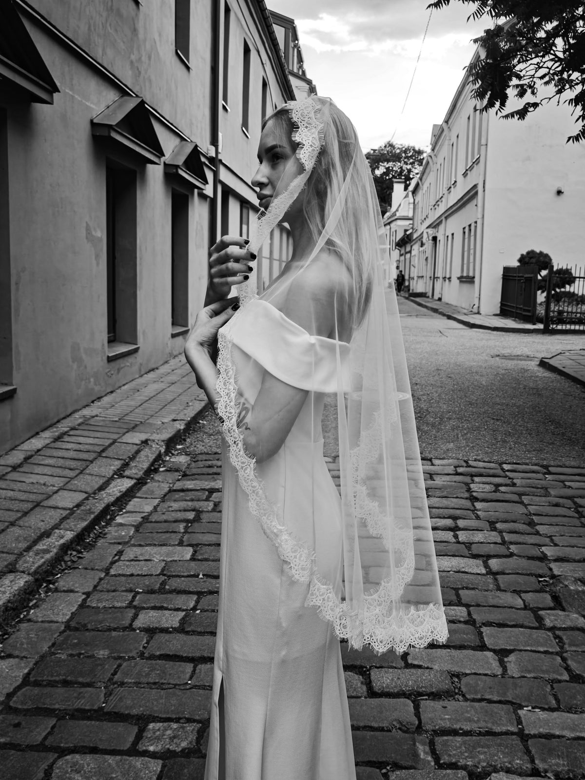 Long simple mantilla veil with delicate scalloped lace edge falling behind a bride, black and white