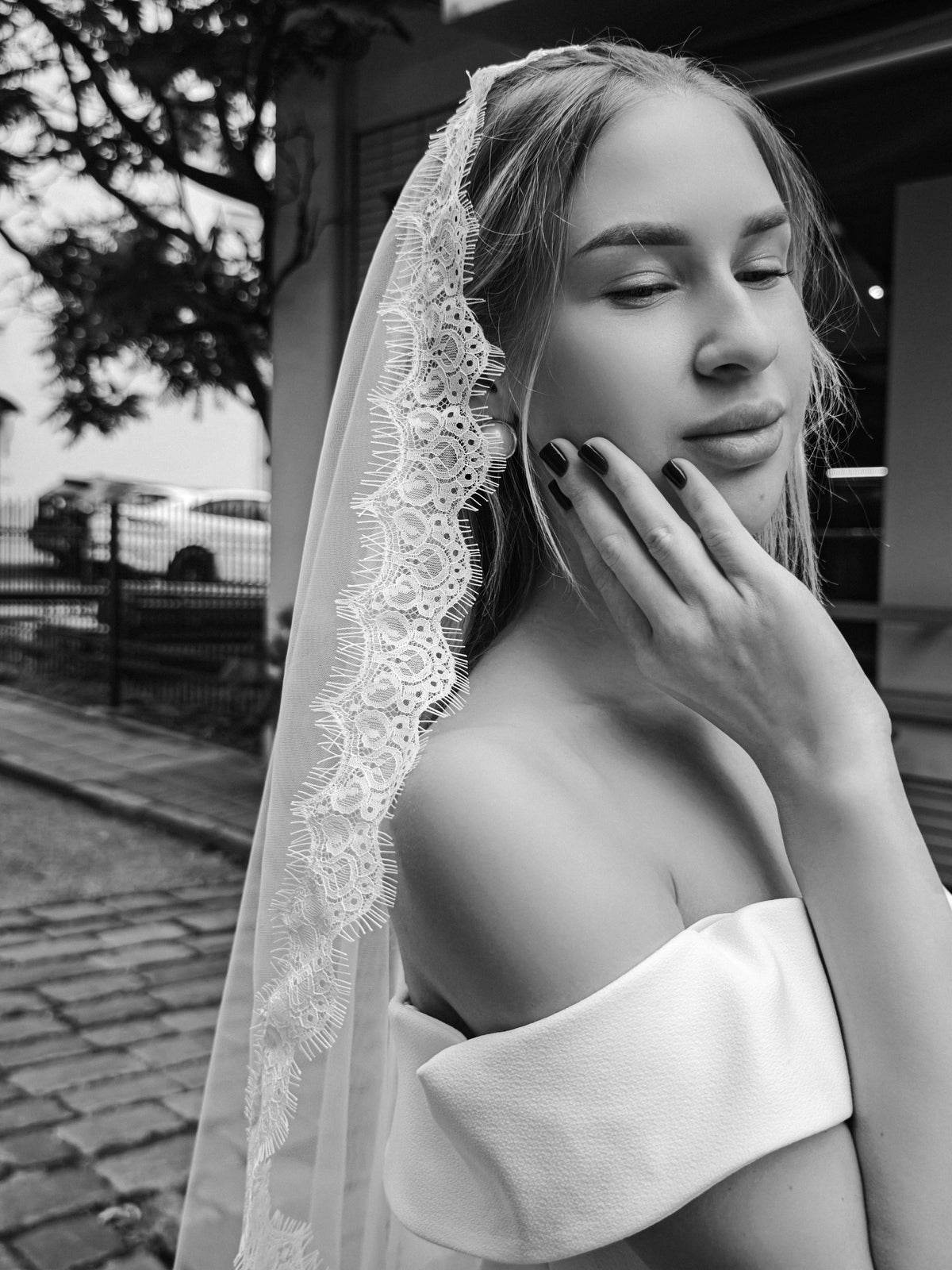 Close portrait of a bride in a mantilla veil, fine Chantilly lace edge framing the face, black and white