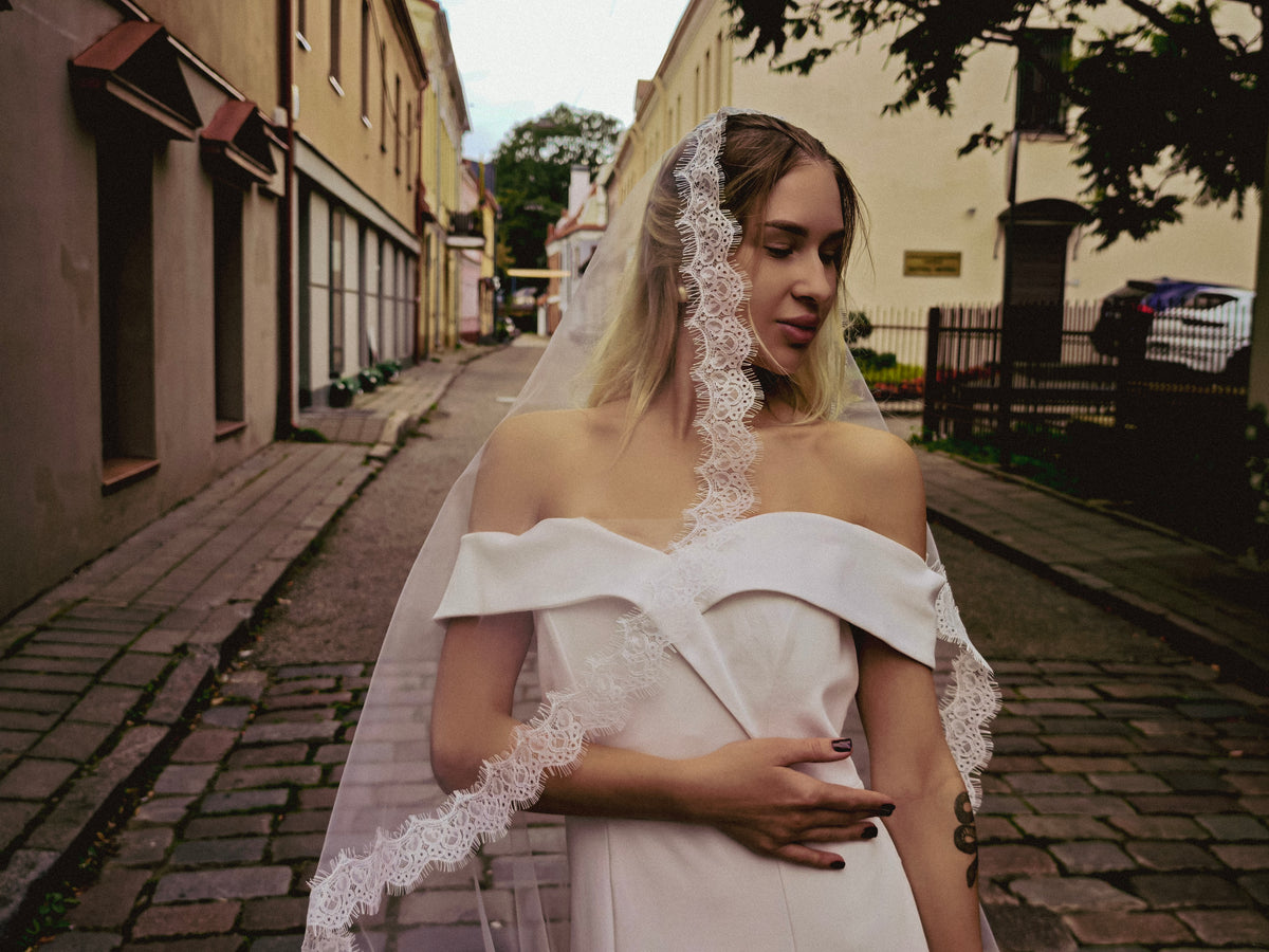 Ivory lace mantilla veil with narrow Chantilly lace border draped over the arms, handcrafted in Europe