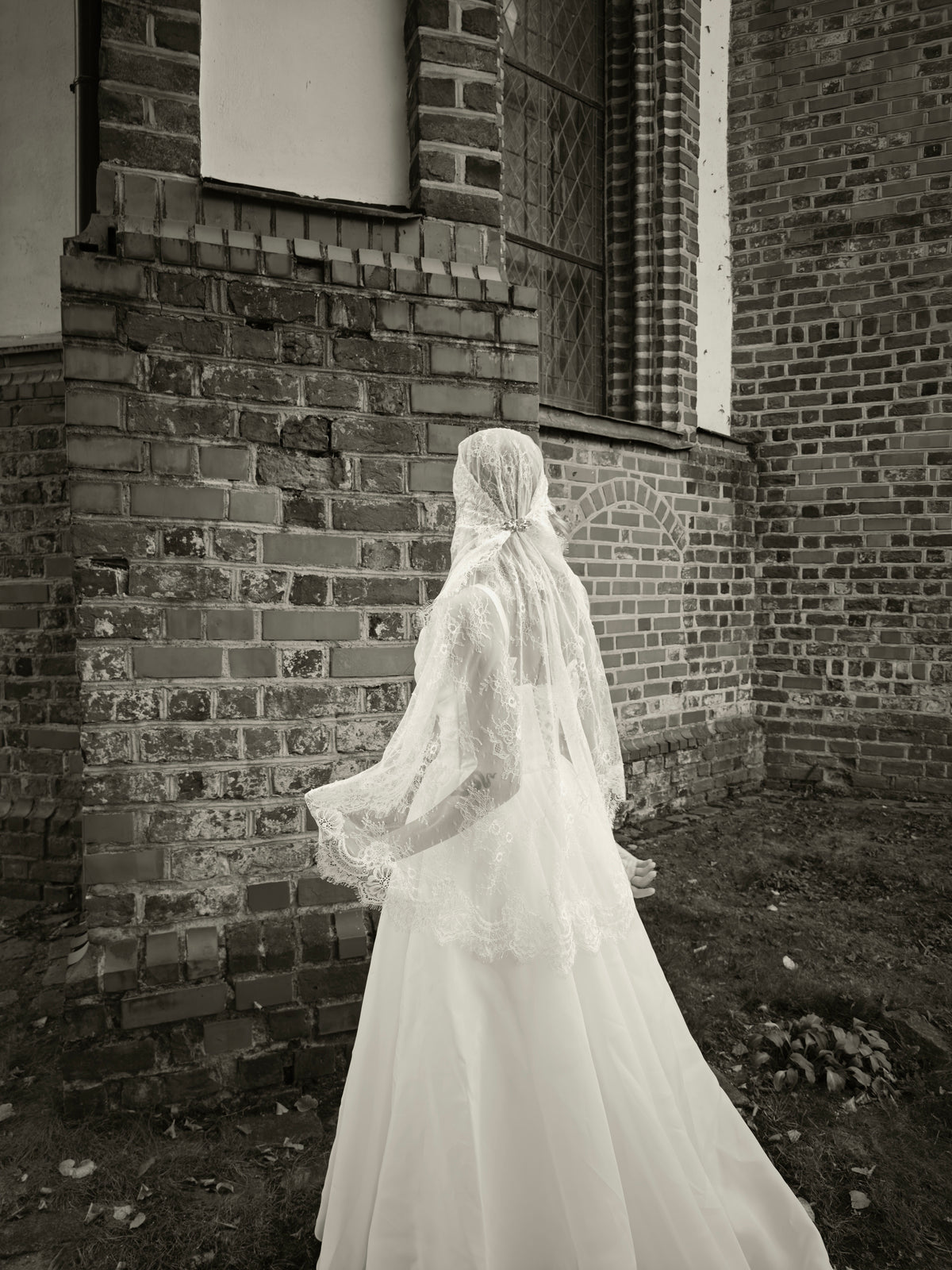 Long lace Juliet cap veil with Chantilly lace edge flowing behind a bride, soft sepia photo