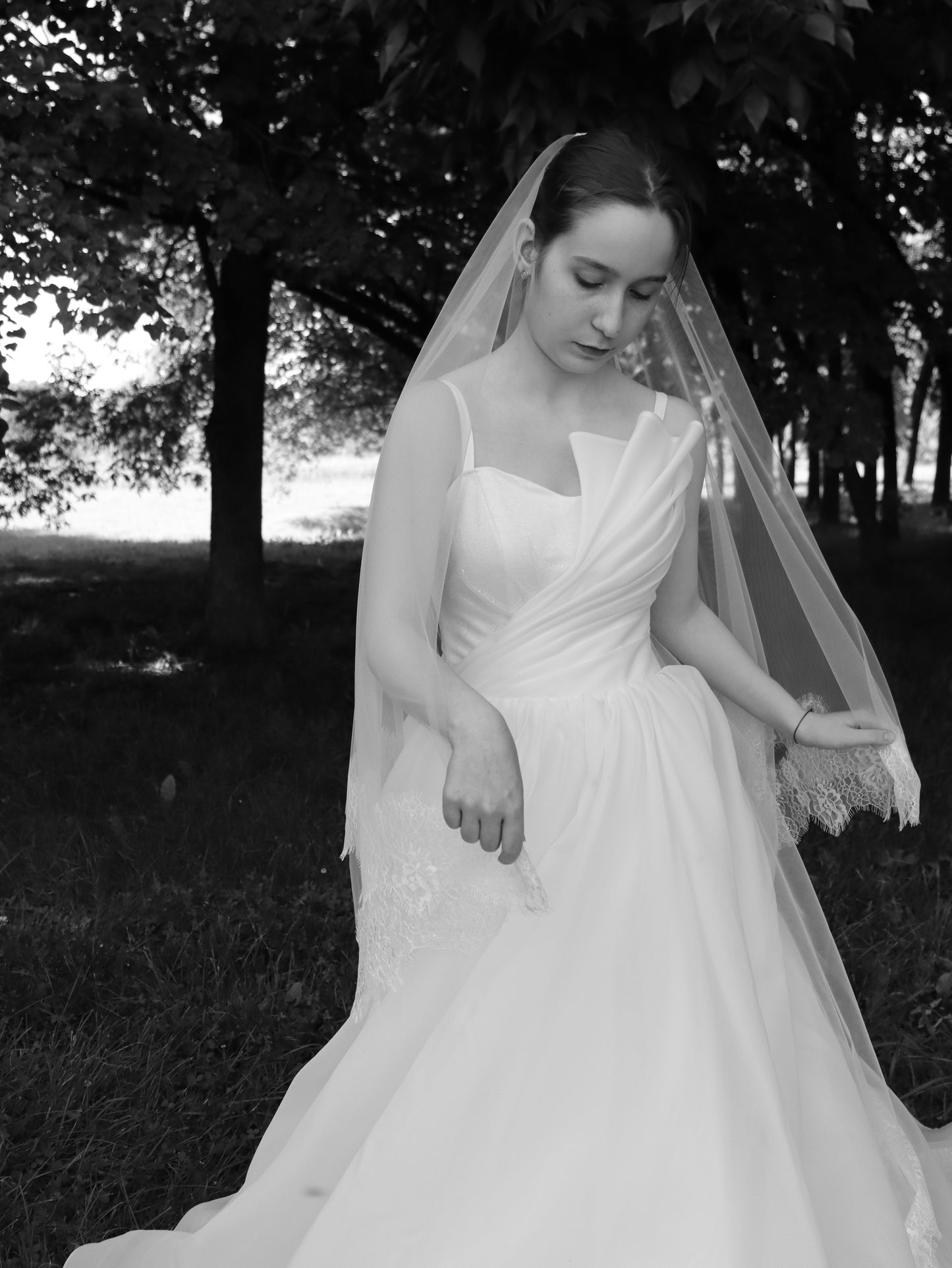 Two-tier bridal veil with floral Chantilly lace trim draped over the shoulders, cathedral length, worn by bride outdoors